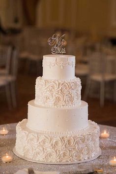 a three tiered white wedding cake sitting on top of a table