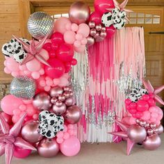 a pink and white balloon arch decorated with stars, balloons, and other decorations for a birthday party