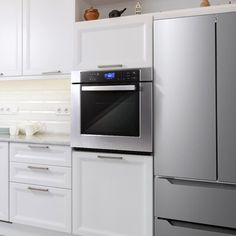 a modern kitchen with stainless steel appliances and white cabinetry, including an oven in the center