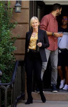 the woman is walking down the stairs with her hand in her pocket and another man standing behind her