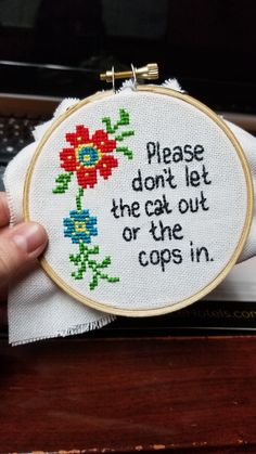 someone is holding up a cross - stitch hoop that says, please don't let the cat out of the cops in