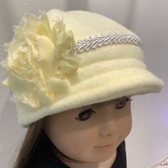 a close up of a doll wearing a white hat with flowers on it's brim