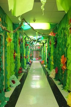 a hallway decorated with paper flowers and streamers on the ceiling is lit by green lights