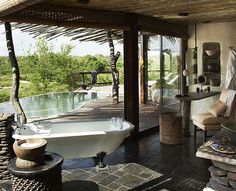 an outdoor bathroom with a tub, sink and large windows on the side of it