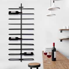 a wine rack is hanging on the wall next to a table with two glasses and a bottle