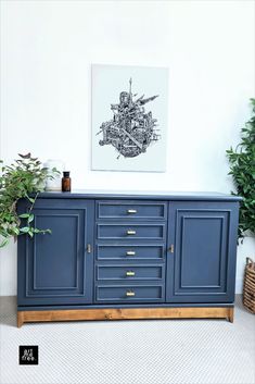 a blue sideboard with gold handles and drawers in front of a painting on the wall