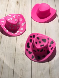 two pink hats with hearts on them sitting on a wooden floor next to each other