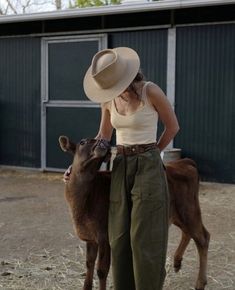 a woman standing next to a brown cow