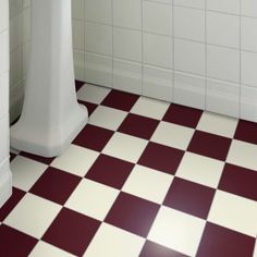 a white pedestal sink sitting next to a toilet in a bathroom with red and white tiles on the floor