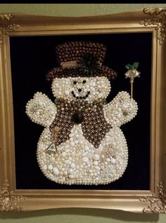 a beaded snowman is displayed in a gold frame