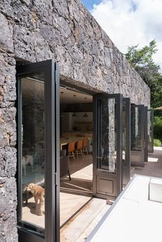 an open door leading to a stone building with a dog in the doorway and tables on either side