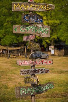 a wooden sign post with many different signs on it's side in the grass