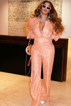 a woman in an orange jumpsuit posing for the camera with her hand on her hip