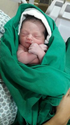 a newborn baby wrapped in a green blanket