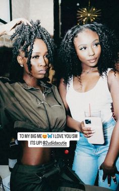 two beautiful young women standing next to each other with drinks in front of their faces