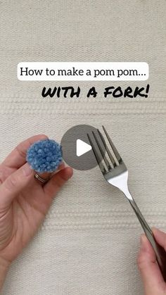 a person holding a fork with a blue pom - pom on top of it