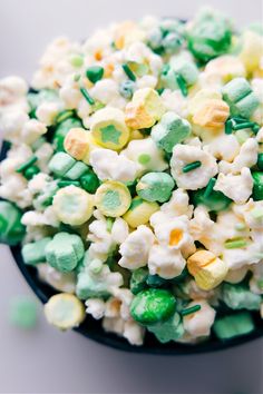 a black bowl filled with green and white candy popcorn mix on top of a table