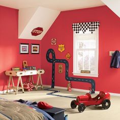 a child's bedroom decorated in red and black with race track decorations on the walls