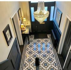 the hallway is decorated in black and white with a chandelier hanging from the ceiling