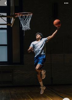 a man is jumping in the air to dunk a basketball into the hoop on an indoor court