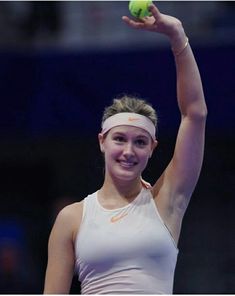 a woman holding a tennis ball up in the air