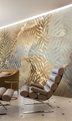 a chair and ottoman in front of a wall with gold leaf designs on it's side