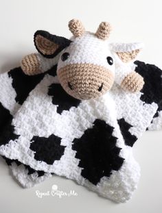 a crocheted cow laying on top of a black and white blanket