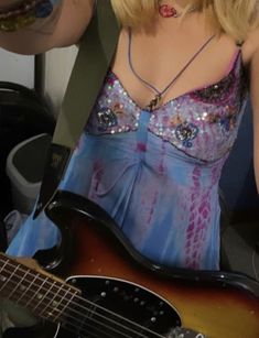 a woman with blonde hair wearing a blue dress and holding an electric guitar in her hand