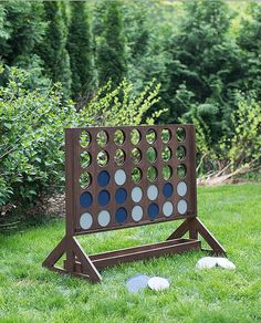 a giant four - sided board game in the grass with trees in the background and bushes to the side