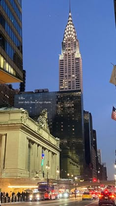 the empire building in new york city is lit up at night with traffic passing by