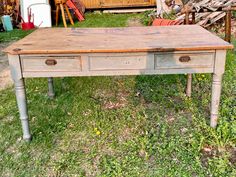 an old wooden table with two drawers in the grass next to other junky items