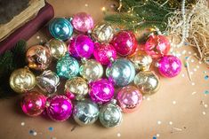 a pile of christmas ornaments sitting on top of a wooden table next to a book