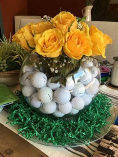 a vase filled with yellow roses and golf balls