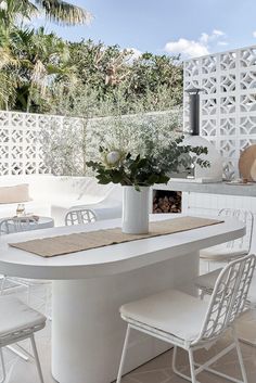 a white table with chairs and a vase filled with flowers sitting on top of it