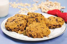 cookies and strawberries on a plate next to a glass of milk