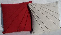 two red and white pillows sitting next to each other on top of a white surface