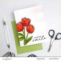 a card with some flowers on it next to scissors and pencils that are sitting on a table