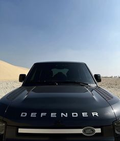 a black car parked in the desert with a dog sticker on it's hood