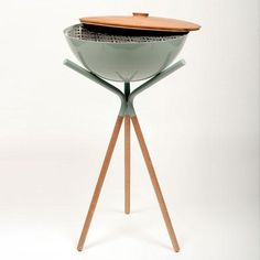 a large green bowl with wooden legs on a white background, sitting on top of a stand