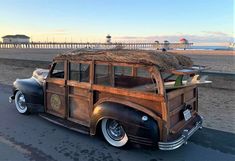 an old car is parked on the side of the road near the beach and pier