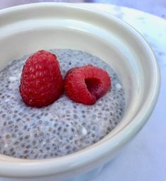 two raspberries sit in a bowl of oatmeal