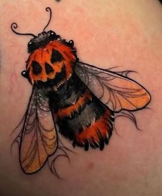 a close up of a tattoo on the back of a woman's shoulder with a bee