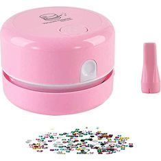 the pink plastic container is next to some colorful beads and a small toothbrush in front of it