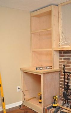 a room that has some tools on the floor in front of a fire place and shelves