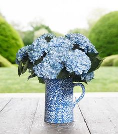 a blue vase filled with flowers sitting on top of a wooden table