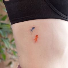 a woman's stomach with two goldfish tattoos on it