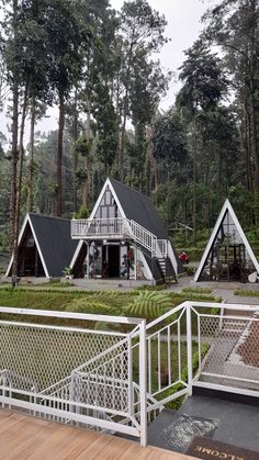 two houses in the middle of a forest with white railings and wooden steps leading up to them