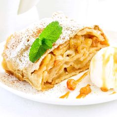 a piece of apple pie on a plate with ice cream and mint leaf garnish