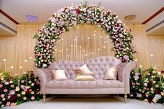 a couch sitting in front of a flower covered wall with candles and flowers on it