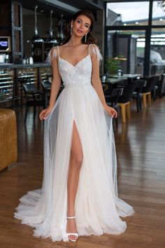 a woman in a white dress standing on a wooden floor with her legs slited